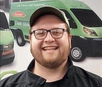 headshot of man with glasses in front of SERVPRO truck poster